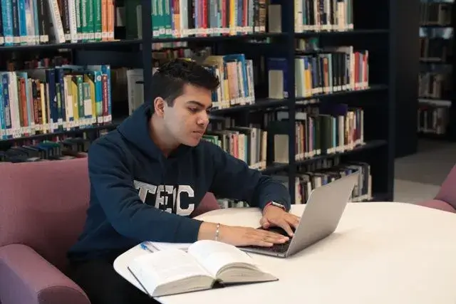 Adolescente estudando online com notebook e caderno.